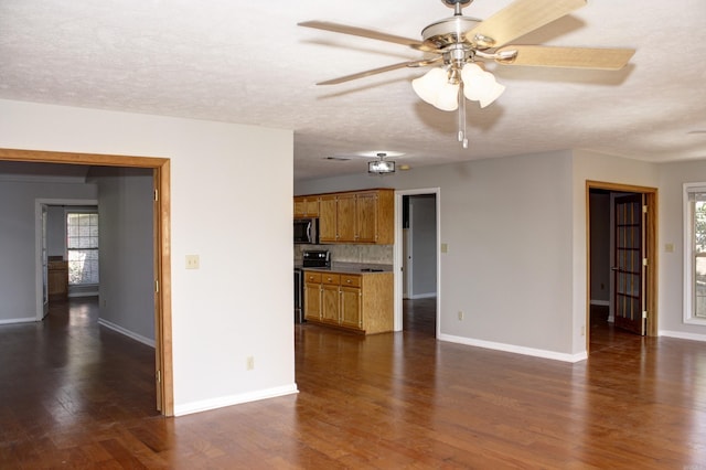 unfurnished living room featuring a textured ceiling, ceiling fan, and dark wood-type flooring