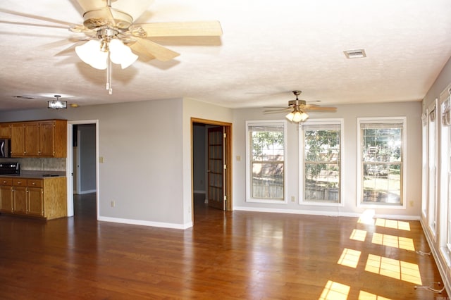 unfurnished living room featuring a textured ceiling, ceiling fan, and dark wood-type flooring