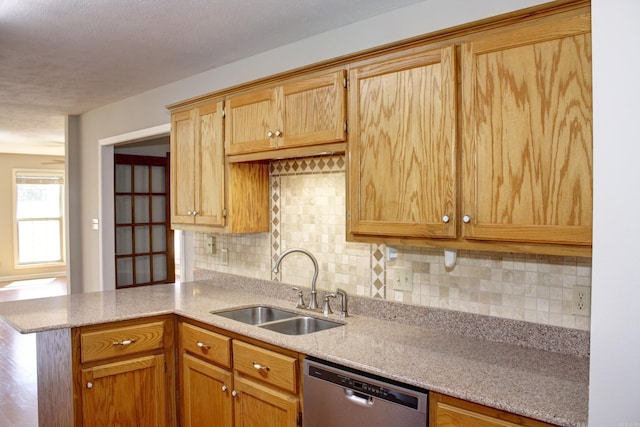 kitchen featuring kitchen peninsula, dishwasher, tasteful backsplash, and sink