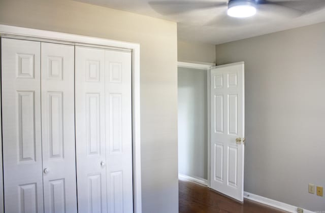 unfurnished bedroom with dark hardwood / wood-style flooring, a closet, and ceiling fan