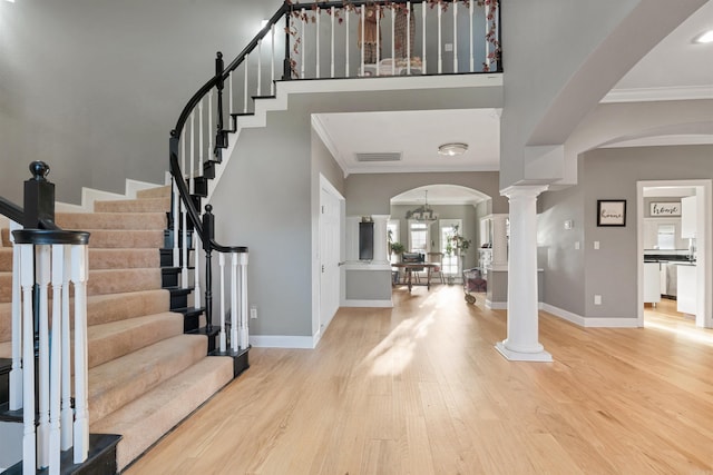 foyer entrance with a notable chandelier, light hardwood / wood-style floors, and crown molding