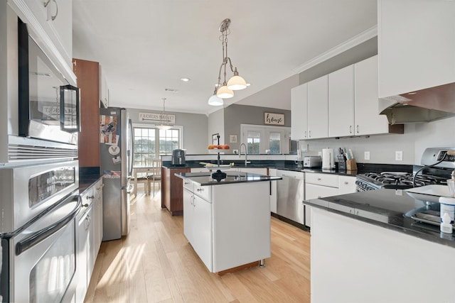 kitchen featuring white cabinetry, stainless steel appliances, hanging light fixtures, a kitchen island, and light hardwood / wood-style flooring