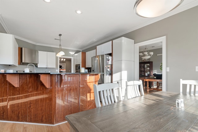 kitchen with crown molding, kitchen peninsula, a notable chandelier, pendant lighting, and white cabinetry