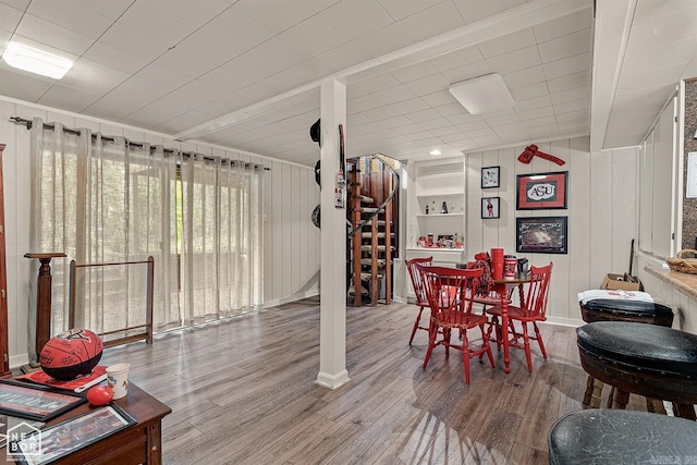 dining area featuring ornamental molding, wood-type flooring, and wooden walls