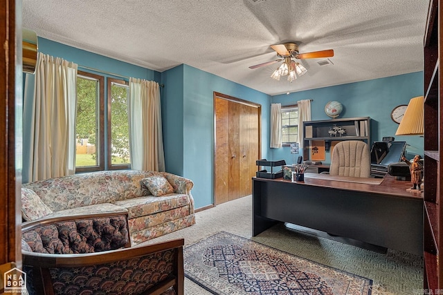 carpeted office space featuring ceiling fan and a textured ceiling