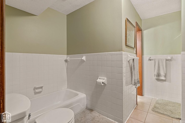 bathroom featuring toilet, tile walls, tile patterned flooring, a tub, and a textured ceiling