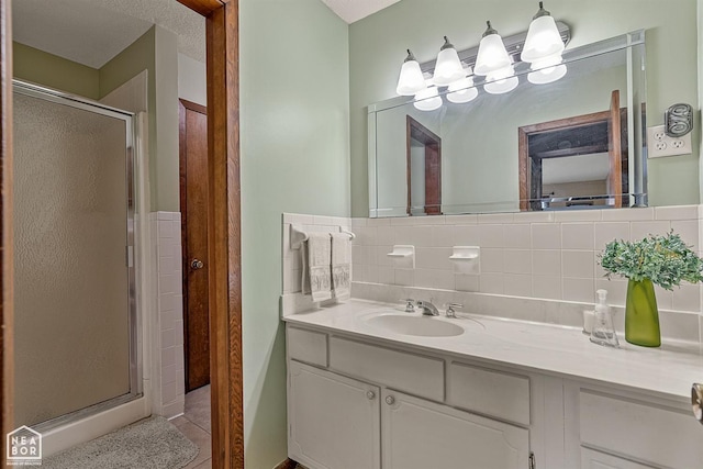 bathroom with decorative backsplash, tile patterned floors, a shower with door, and vanity