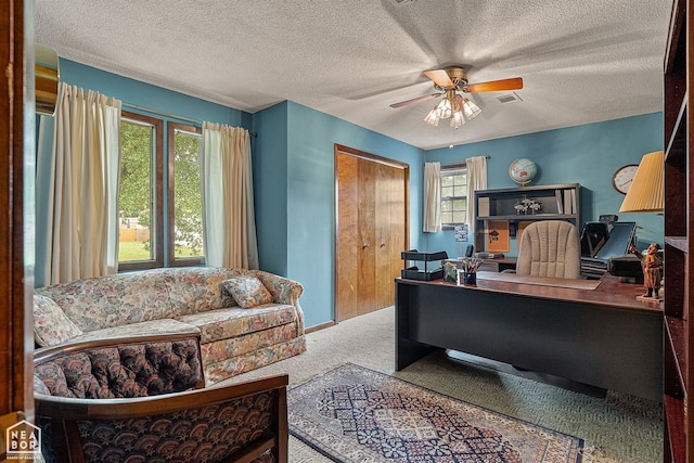 carpeted office space featuring ceiling fan and a textured ceiling