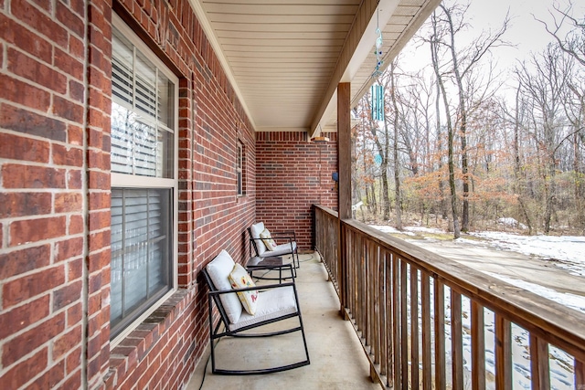 snow covered back of property featuring a porch