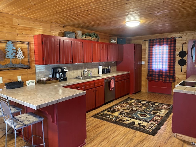 kitchen featuring dishwasher, wooden ceiling, tile counters, light hardwood / wood-style floors, and sink