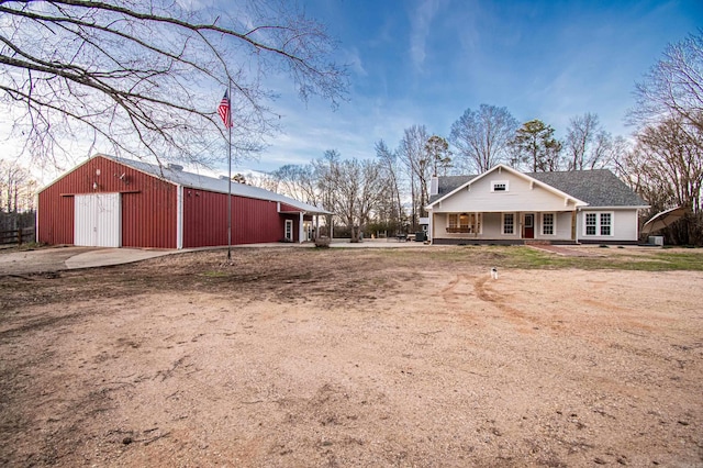 view of yard featuring a garage, a porch, and an outdoor structure