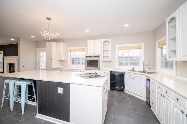 kitchen featuring stainless steel appliances, a kitchen island, white cabinets, and sink