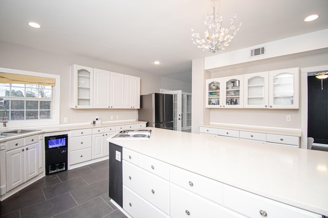 kitchen featuring sink, refrigerator, decorative light fixtures, and white cabinetry