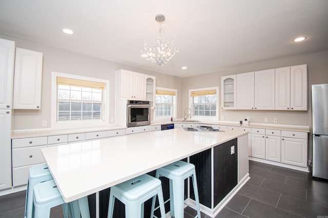 kitchen featuring hanging light fixtures, stainless steel appliances, a kitchen island, a breakfast bar area, and white cabinets