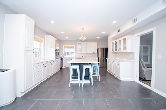 kitchen with stainless steel appliances, white cabinetry, a center island, and pendant lighting