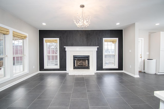 unfurnished living room with a notable chandelier and a brick fireplace