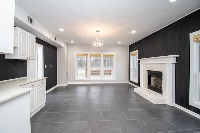 kitchen featuring decorative light fixtures, white cabinetry, an inviting chandelier, a brick fireplace, and dark tile patterned floors