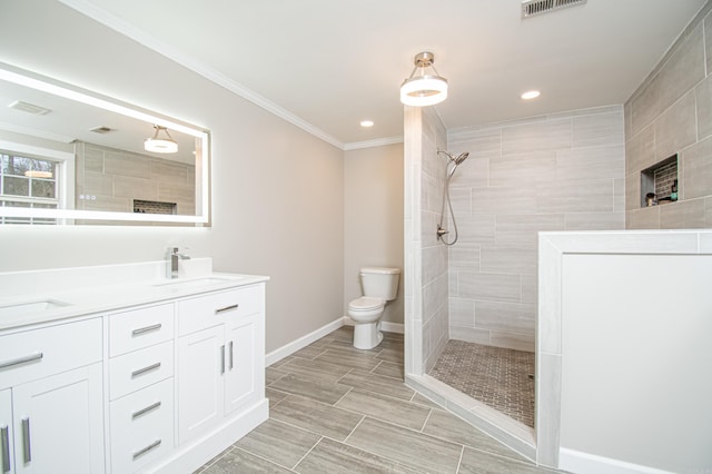 bathroom with crown molding, a tile shower, vanity, and toilet