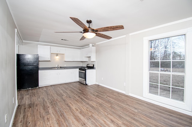 kitchen with white cabinetry, stainless steel gas range, black refrigerator, ceiling fan, and wood-type flooring