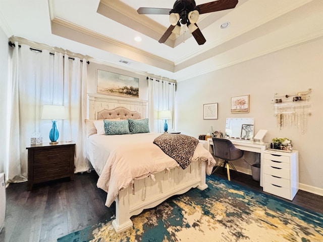 bedroom featuring ceiling fan, a tray ceiling, crown molding, and dark wood-type flooring