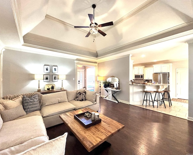 living room with ceiling fan, a tray ceiling, crown molding, and light hardwood / wood-style flooring