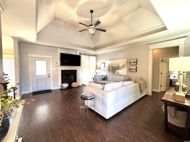 living room featuring ornamental molding, ceiling fan, dark hardwood / wood-style floors, and a tray ceiling