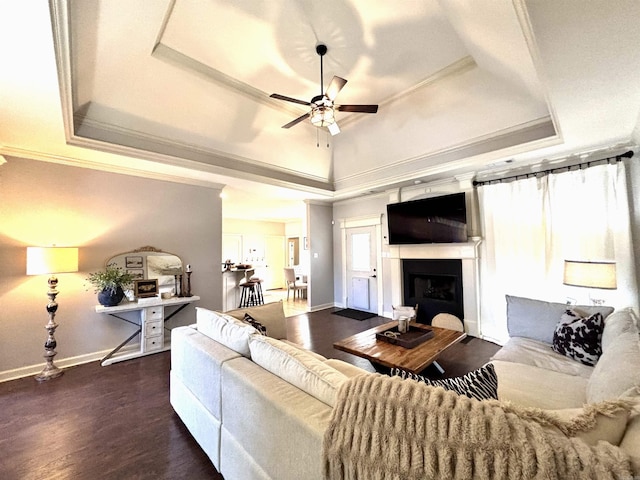 living room featuring ceiling fan, dark hardwood / wood-style flooring, a raised ceiling, and crown molding