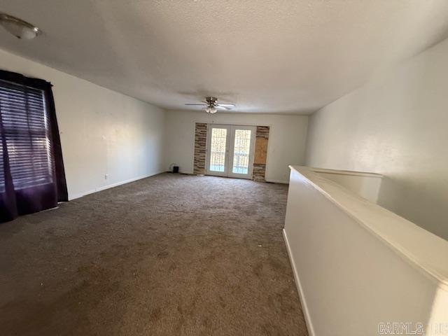 carpeted empty room featuring ceiling fan, french doors, and a textured ceiling