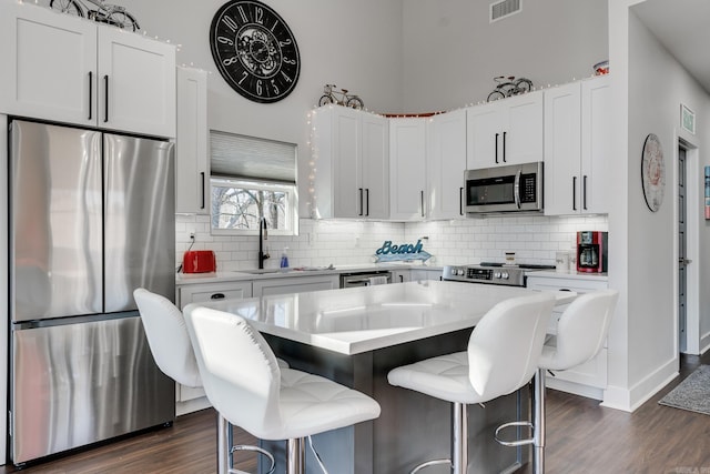 kitchen featuring stainless steel appliances, white cabinetry, a kitchen bar, and a kitchen island