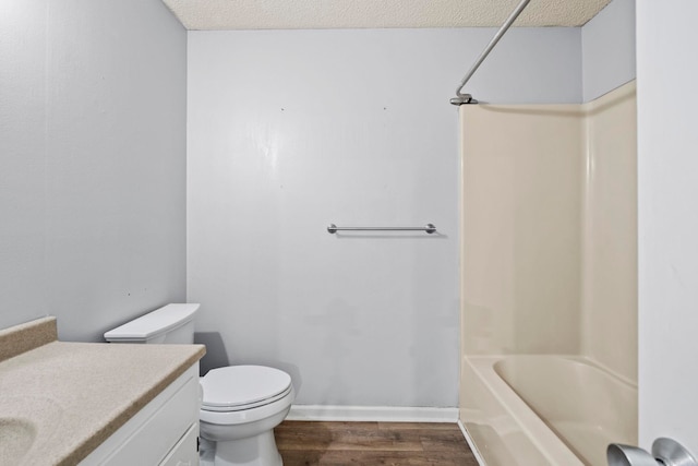 full bathroom featuring toilet, a textured ceiling, bathtub / shower combination, hardwood / wood-style floors, and vanity