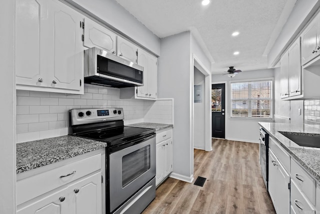 kitchen featuring light stone countertops, a textured ceiling, stainless steel appliances, white cabinetry, and ceiling fan