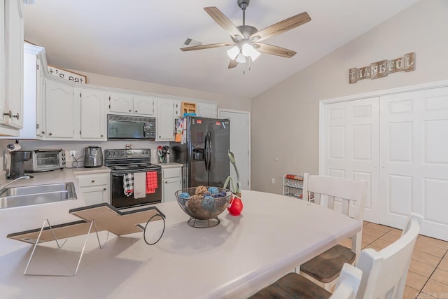 kitchen featuring vaulted ceiling, light tile patterned floors, black appliances, white cabinets, and sink