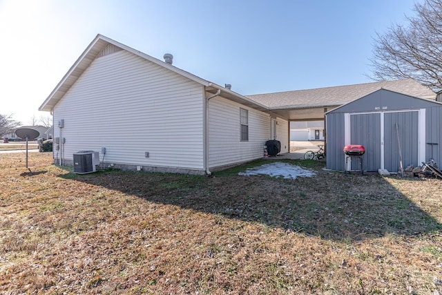 view of property exterior with a yard, central AC unit, and a storage shed