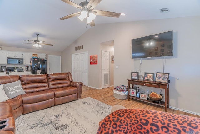 living room with ceiling fan, light wood-type flooring, and vaulted ceiling