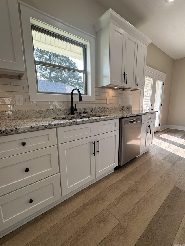 kitchen featuring white cabinets, light hardwood / wood-style floors, dishwasher, and light stone countertops