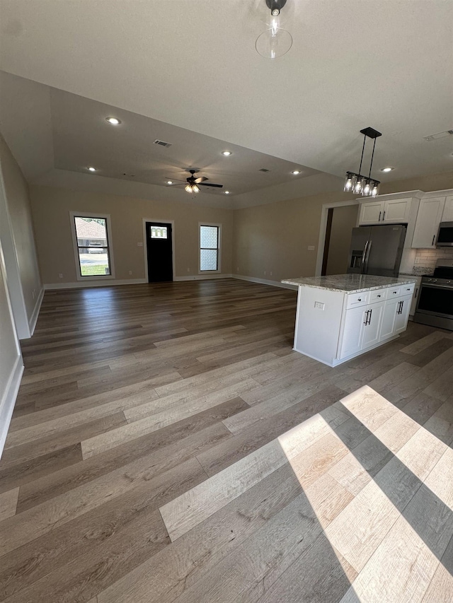 kitchen with decorative light fixtures, stainless steel appliances, light hardwood / wood-style floors, a kitchen island, and white cabinetry