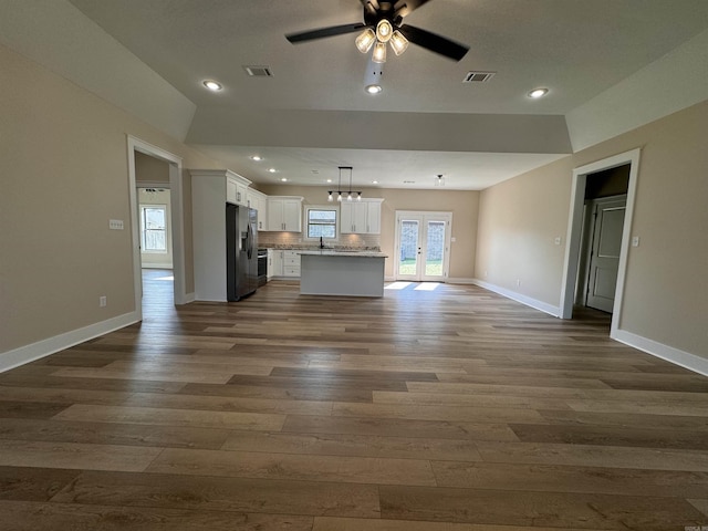 unfurnished living room featuring ceiling fan with notable chandelier, french doors, sink, and dark hardwood / wood-style floors