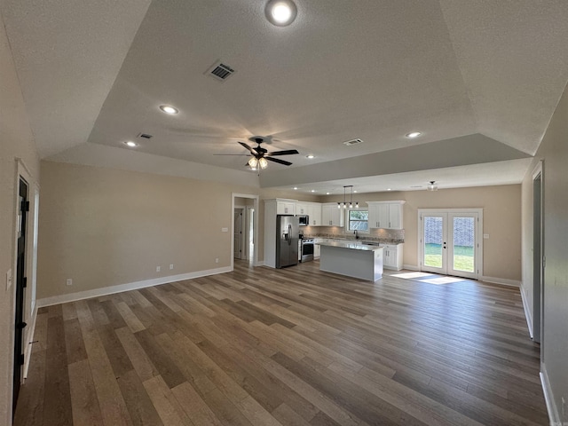 unfurnished living room with a raised ceiling, a textured ceiling, ceiling fan, and hardwood / wood-style flooring