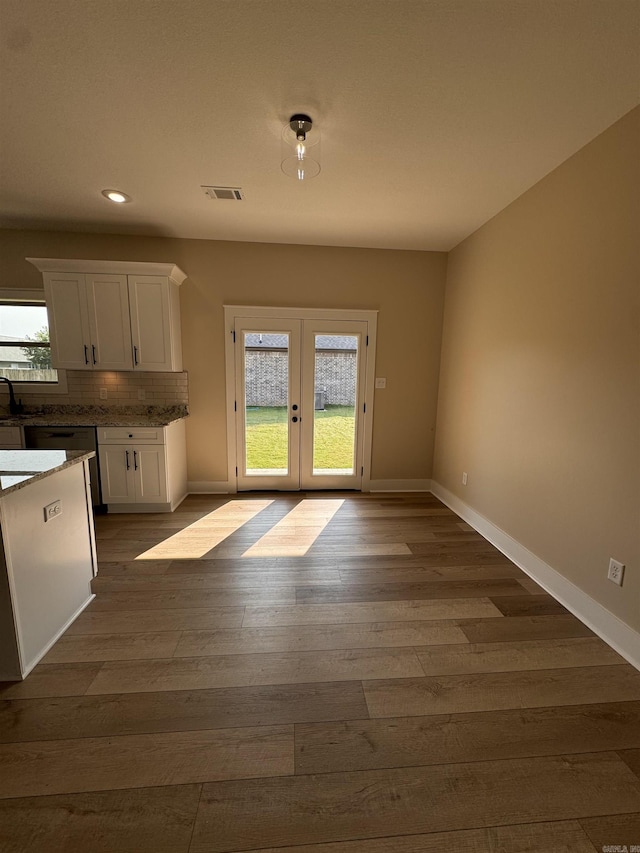 kitchen with french doors, white cabinetry, a wealth of natural light, and tasteful backsplash