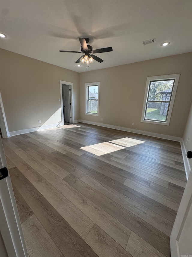 spare room featuring ceiling fan, wood-type flooring, and plenty of natural light