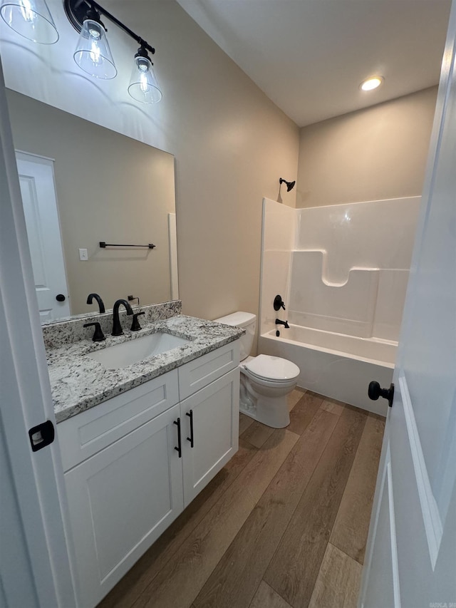 full bathroom with toilet, wood-type flooring, vanity, and shower / washtub combination