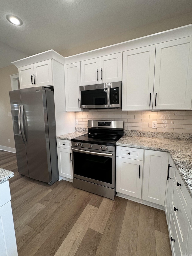 kitchen with white cabinets, light wood-type flooring, and appliances with stainless steel finishes