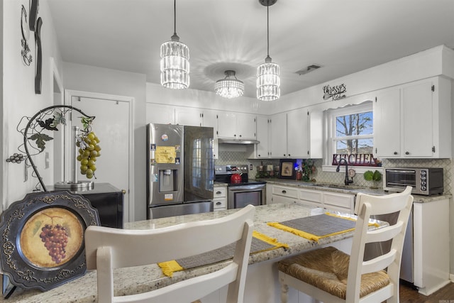 kitchen featuring light stone countertops, pendant lighting, a notable chandelier, white cabinetry, and appliances with stainless steel finishes