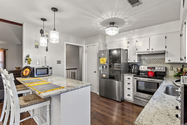 kitchen with hanging light fixtures, stainless steel appliances, tasteful backsplash, a breakfast bar area, and white cabinetry