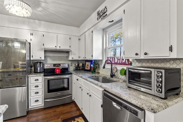 kitchen featuring stainless steel appliances, white cabinets, a chandelier, and sink