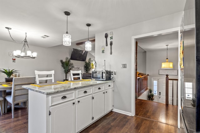 kitchen with white cabinets, pendant lighting, light stone counters, and dark wood-type flooring