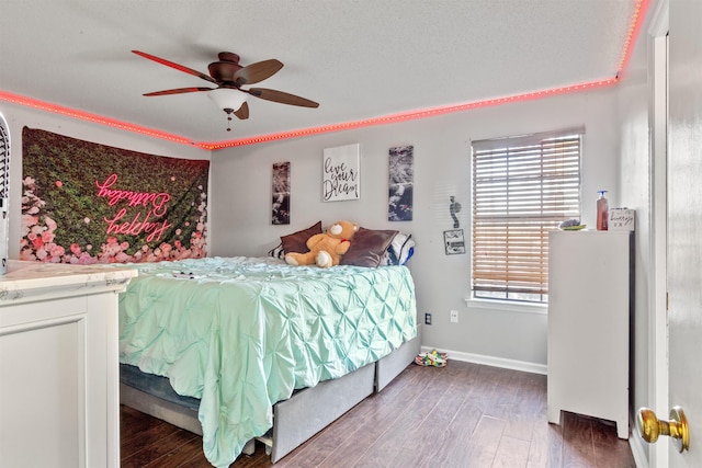 bedroom with ceiling fan, dark wood-type flooring, multiple windows, and a textured ceiling