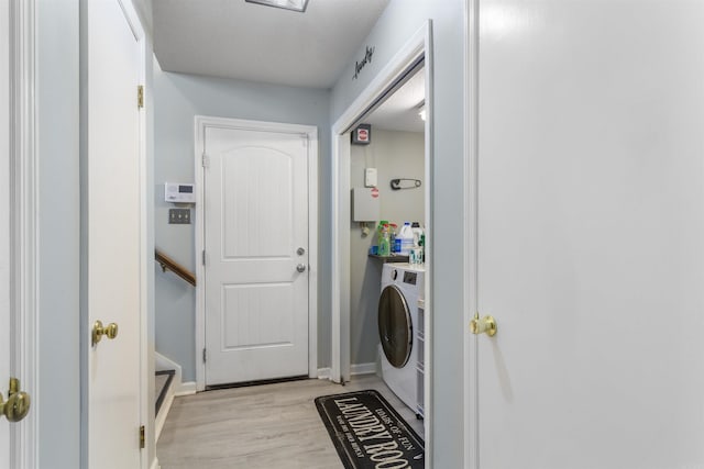 clothes washing area featuring washer / clothes dryer and light hardwood / wood-style floors