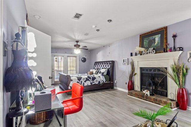 bedroom featuring ceiling fan, light hardwood / wood-style floors, and a fireplace