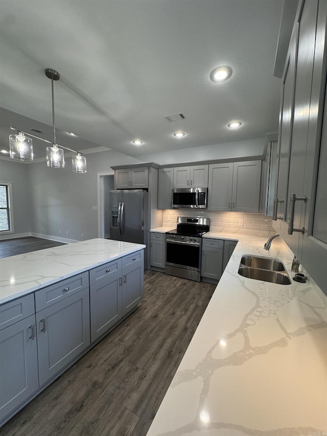 kitchen featuring sink, light stone counters, decorative backsplash, pendant lighting, and appliances with stainless steel finishes